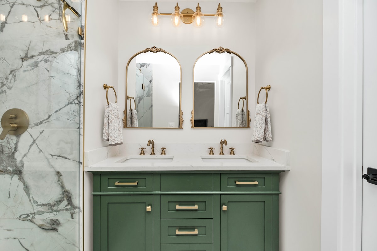 A bathroom vanity with drawers under a stone top and a wall-mounted mirror